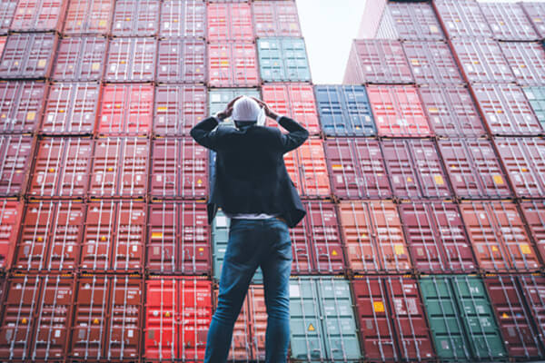 Man looking up at stacks of commercial shipping containers 